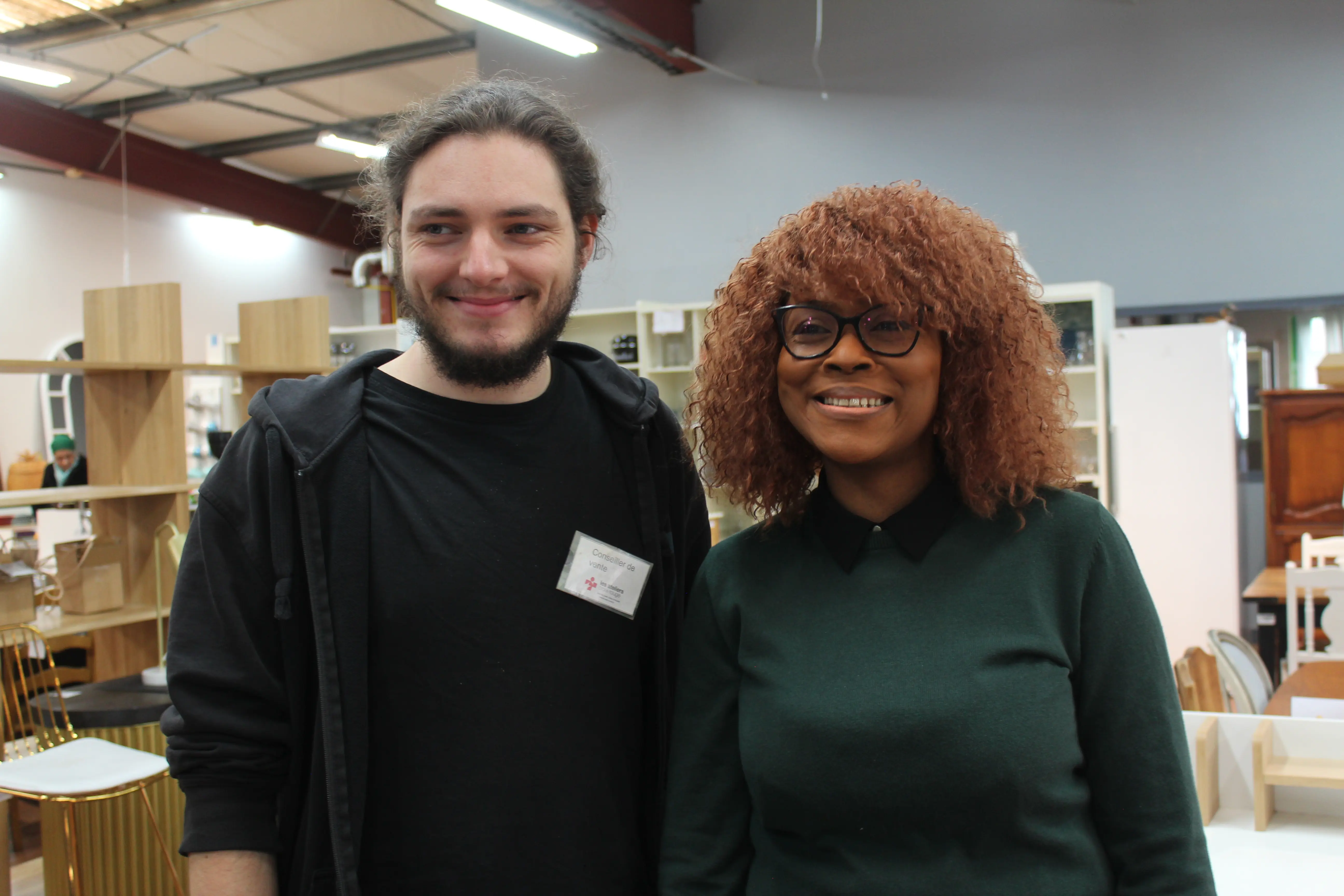 Bénévole et salarié·e en parcours d'insertion souriant ensemble en boutique solidaire